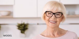 Older Female Patient Smiling with Dental Implants in Kitchen